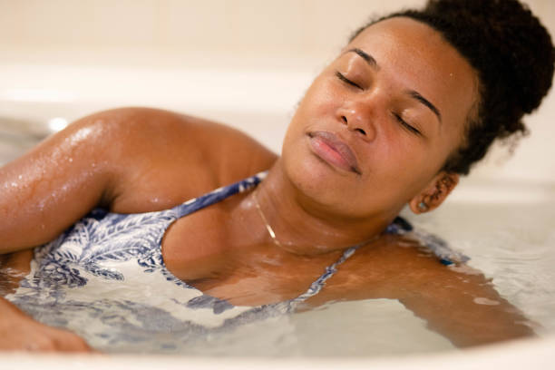 jeune femme assise les yeux fermés dans un bain à remous - hidromassage inside of wet luxury photos et images de collection