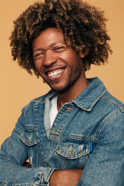istock Confident cheerful black man smiling at camera in beige studio 1477941369