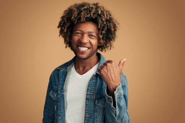 istock Delighted young black guy pointing away against brown background 1477941375