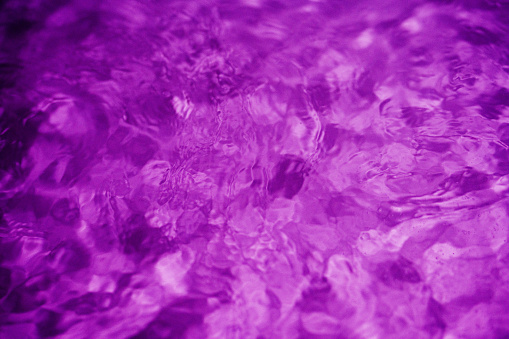 Close-up of the surface of water illuminated in purple of a hot tub in the evening