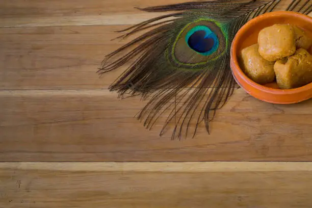 Photo of Mathura ka peda is served on a clay plate with peacock feather during celebration of Krishna janmashtami. This traditional Indian sweet originated in mathura is made of khoya or Mawa, ghee and sugar.