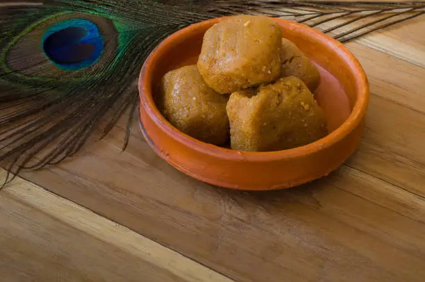 Photo of Mathura ka peda is served on a clay plate with peacock feather during celebration of Krishna janmashtami. This traditional Indian sweet originated in mathura is made of khoya or Mawa, ghee and sugar.