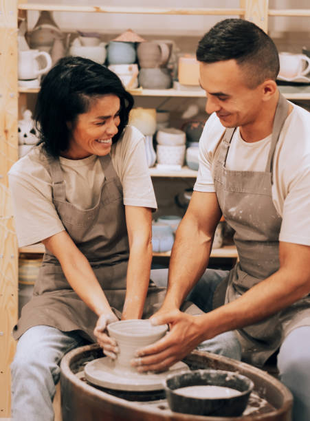 Couple in love working together on potter wheel in craft studio workshop. stock photo