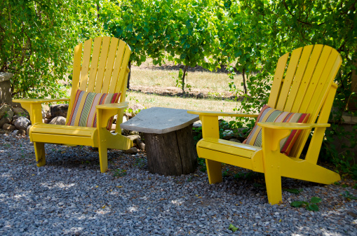 Two yellow Adirondack chairs with colorful cushions in a winery restaurant.