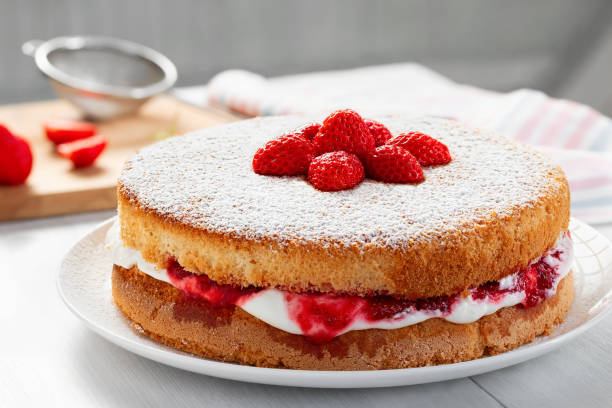 двухслойный торт виктория со взбитыми сливками, клубничным вареньем и свежими ягодами, крупным планом - бисквитный торт стоковые фото и изображения