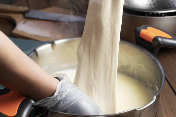 Making mozzarella cheese. Pulling out the cheese clot after heating in whey