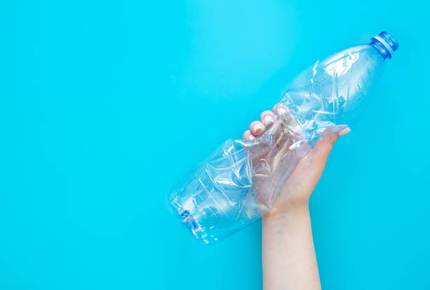 istock Used plastic bottle in a female hand on a blue background, top view. 1477960473