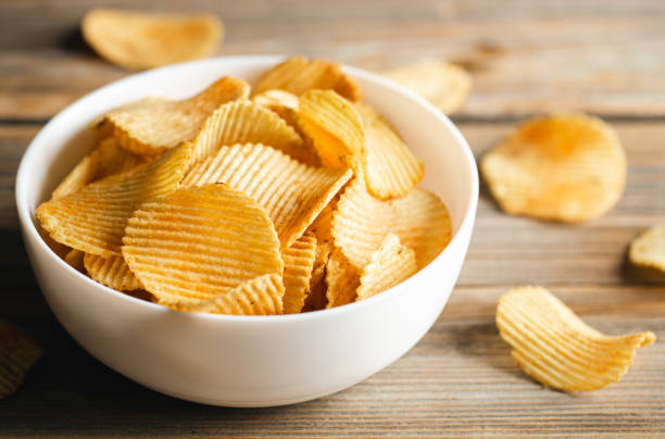 istock Potato chips in a bowl on a wooden background, close up. 1477961522