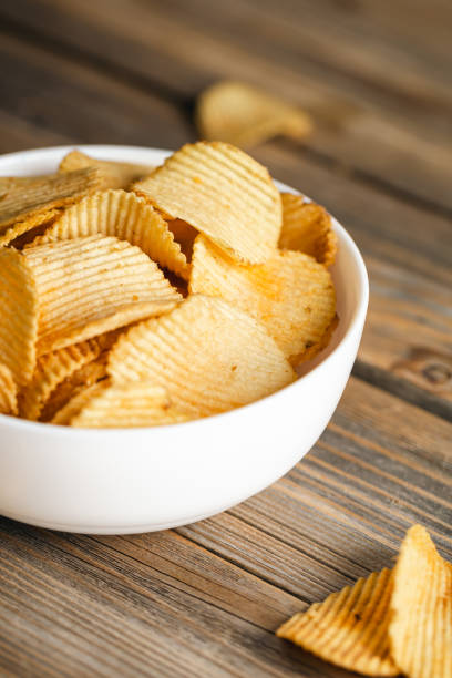 istock Potato chips in a bowl on a wooden background, close up. 1477961632