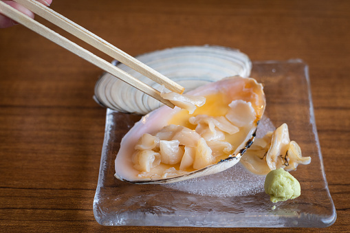 A close up of chopped up raw clam meat served in its shell ready to eat.