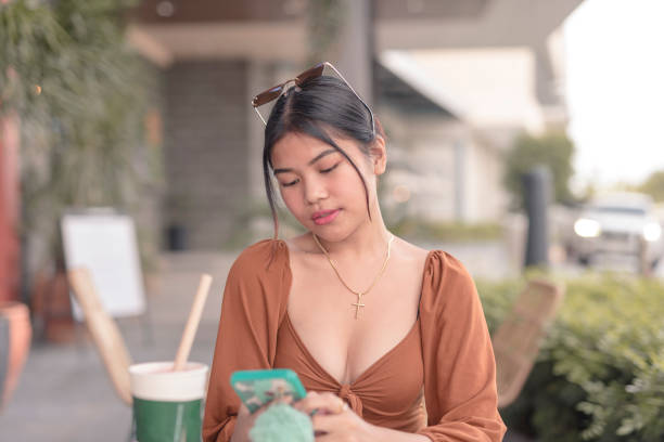 uma filipina navega na internet usando seu celular em um café no início da manhã enquanto espera por sua comida. - puffed sleeve - fotografias e filmes do acervo