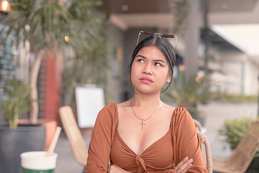 A young asian woman puts on an annoyed facial expression after being offended from hearing an awful insult or insensitive comment.