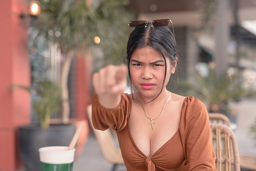 A resentful young girl points at the camera with full rage on her face. Blaming someone for her bad day.