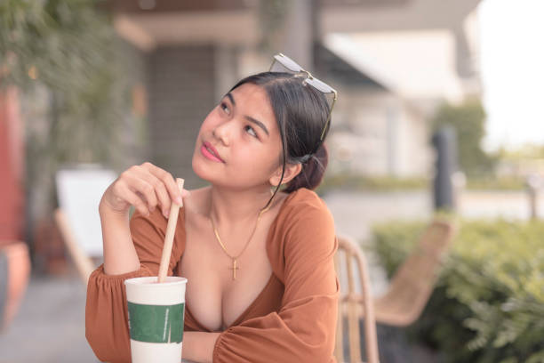 привлекательная дама в коричневом пышном п�латье с длинными рукавами сидит возле кафе со своим холодным напитком. - puffed sleeve стоковые фото и изображения