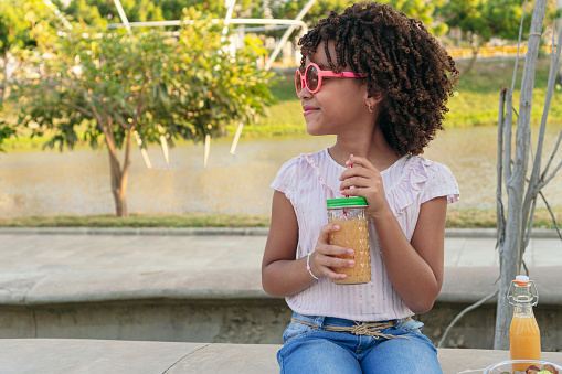Girl in a park with a glass of healthy juice