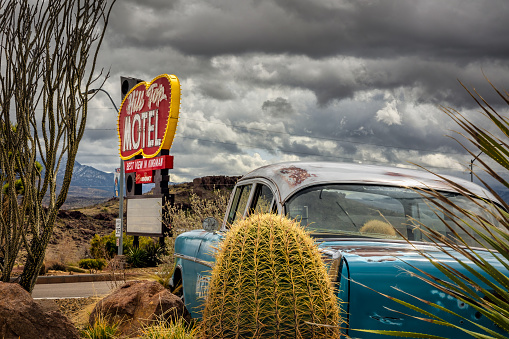 Kingman, Arizona, USA - March 11, 2023: Cactus and an old car sit in front of the Hill Top Motel with the best view in town.