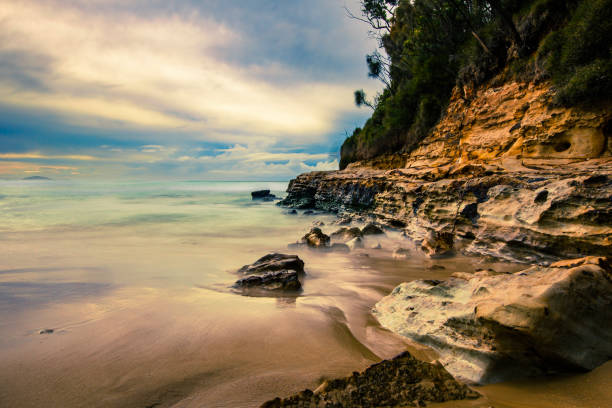 Rocky beach  with tidal waves washing over golden rocks. Coastal seascape scene in NSW, Australia.