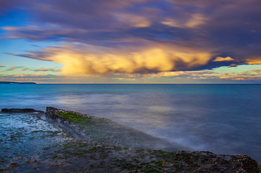 Rolling storm cell over a smooth ocean illuminated by the setting sun. Coastal seascape scene in NSW, Australia.