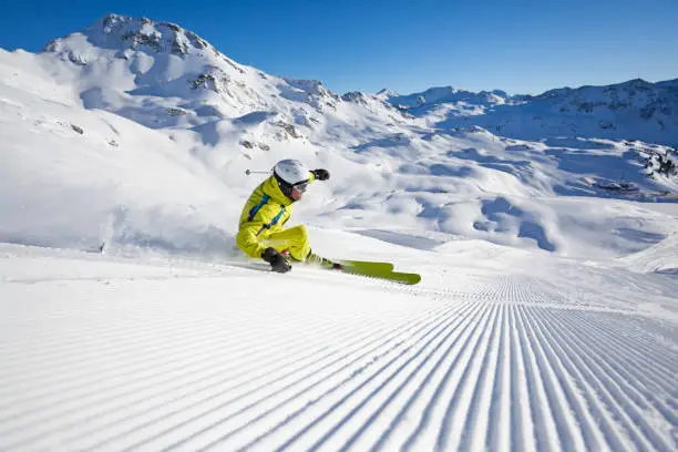 skier in sloping position carving on wonderful skiing slope in austrian mountains