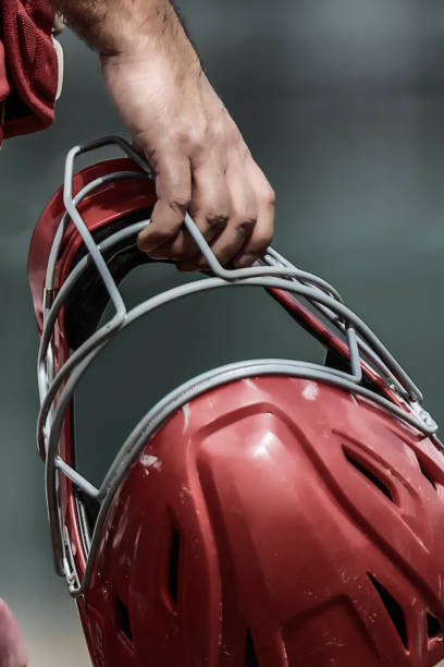 Catcher Holding Mask Baseball catcher holding his hockey-style face mask before the start of an inning, closeup of right hand, no faces shown in photograph catchers mask stock pictures, royalty-free photos & images