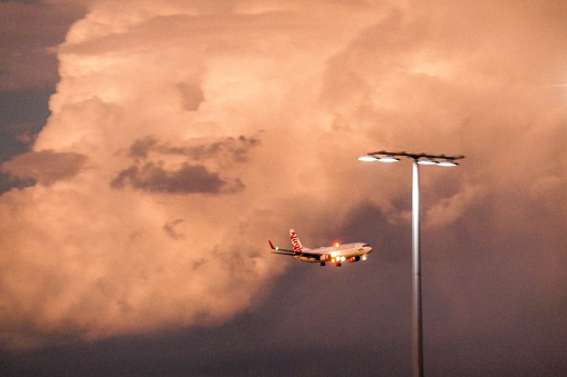 A Virgin Australia Boeing B737-800 comes into land with storm clouds passing over Sydney Kingsford-Smith Airport. Shortly after this, the airport was briefly closed because of the severe weather conditions and some planes diverted to other airports.  This image was taken from Shep's Mound, a public viewing area off Ross Smith Avenue, Mascot at sunset on 10 February 2023.