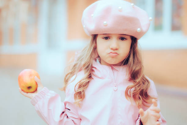 petite fille en bas âge n’aimant pas grignoter en bonne santé tenir une pomme - eating obsessive child toddler photos et images de collection