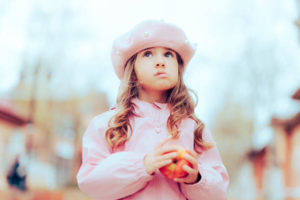 une petite fille tenant une pomme qui pense à une alimentation saine - eating obsessive child toddler photos et images de collection