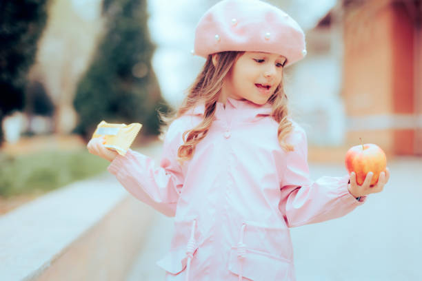 une petite fille décide entre des aliments transformés sains et malsains - eating obsessive child toddler photos et images de collection