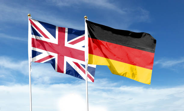 union jack y bandera alemana en cielo nublado. ondeando en el cielo - british empire flag global uk fotografías e imágenes de stock