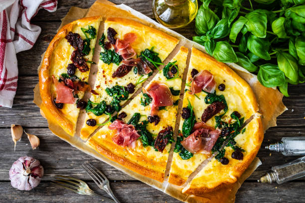 istock Pizza prosciutto with spinach, sun dried tomatoes and mozzarella on wooden background 1477990623