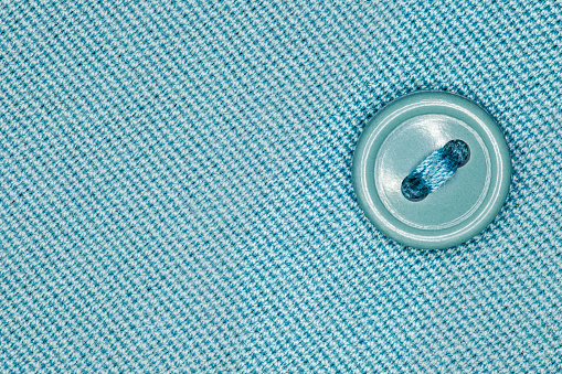 Button close-up down with threads to a green fabric
