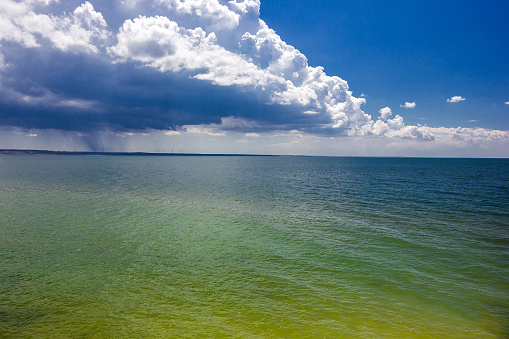 Sea, seascape waves on water on clear day and thunder clouds with rain in background