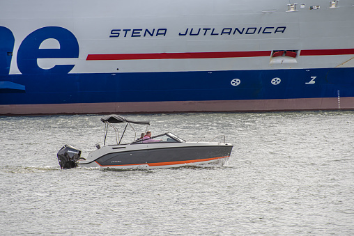 Gothenburg, Sweden - May 04 2022: Powerboat cruising down the river in front of a ferry.