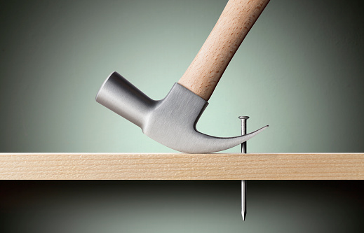 Using a claw hammer to remove a nail from timber.