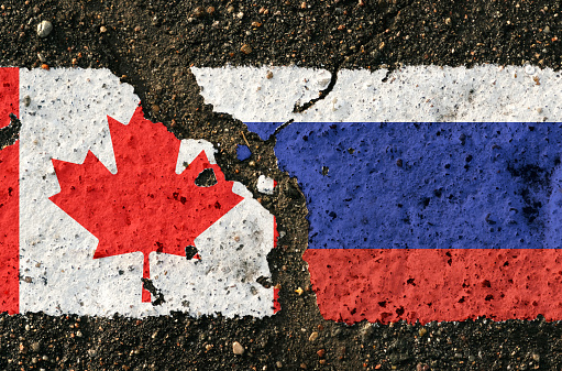 On the pavement are images of the flags of Canada and Russia, as a symbol of the confrontation between countries. Conceptual image.