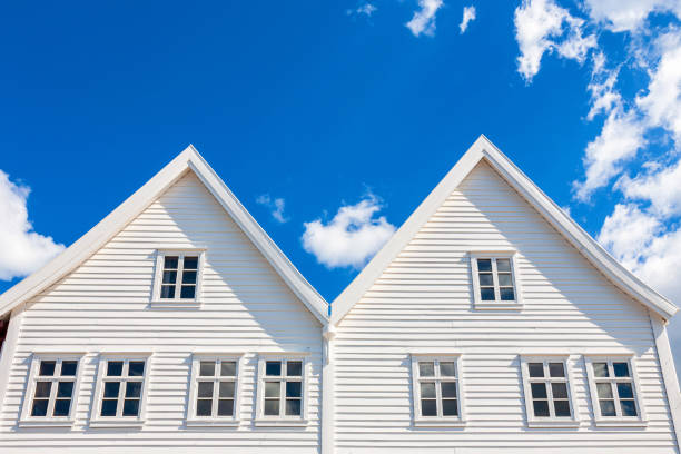 Three white wooden house facade in Sogndal, Norway, photographed on a sunny summer day with roses by the street.