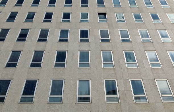 istock Large office building facade made of rectangle windows and gray stone tiles. 1477998762