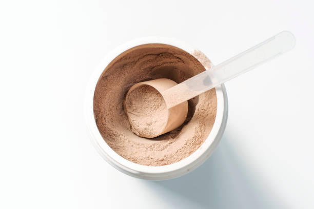 istock Chocolate protein powder in a scoop against plastic jar on white background. 1477998925