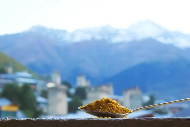 Photo of Closeup a Spoon of Georgian Svan Salt with Blurry Caucasus Mountains and Mestia Town in the Backdrop