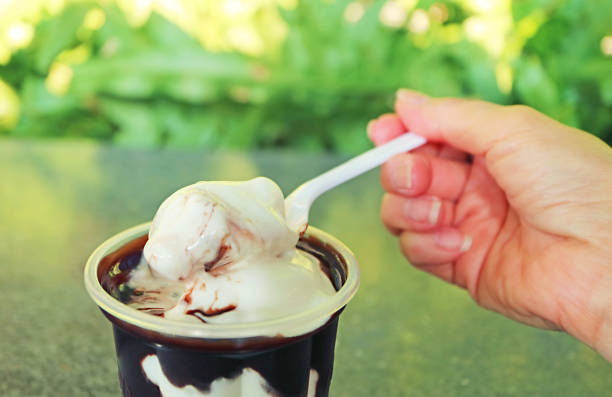 istock Hand Scooping Melting Chocolate Sauced Vanilla Soft Serve Ice Cream with Spoon 1478002596
