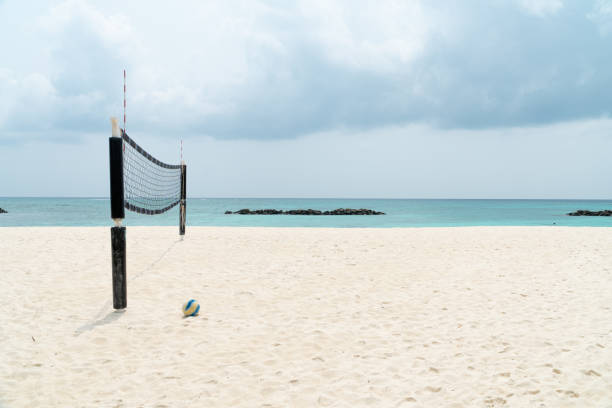 view of a beach volleyball court with net and a ball in the sand - volleyball beach volleyball beach sport imagens e fotografias de stock