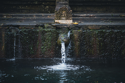 A pool with flowing water in the Tirta Empul temple, Bali, Indonesia.
