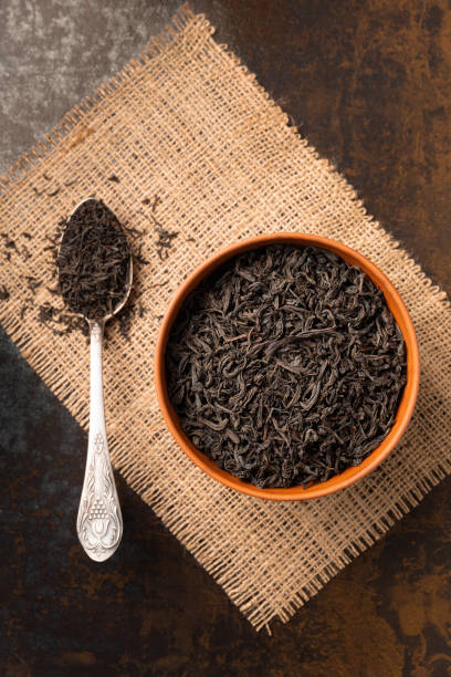 istock Dry black tea in a bowl and a spoon on a dark background 1478014808
