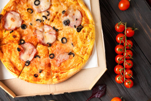 istock Pizza in a box on a dark wooden background top view space for text. 1478015158