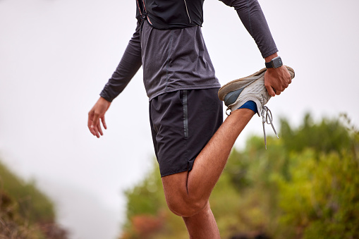 Exercise, balance and man stretching legs on nature trail for running, marathon training and cardio workout. Sports, healthy body and torso of male athlete warm up for wellness, energy and fitness