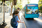 Man and young son standing at bus stop as vehicle approaches