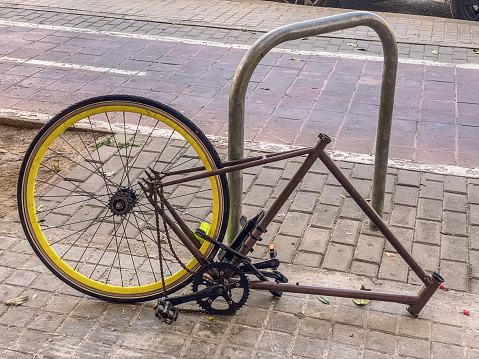 Bicycle frame hooked to pole in the street with its front section missing