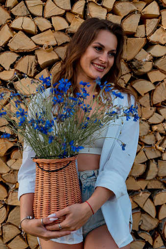 Beautiful amazing gorgeous brunette girl posing with flowers on the background of firewood