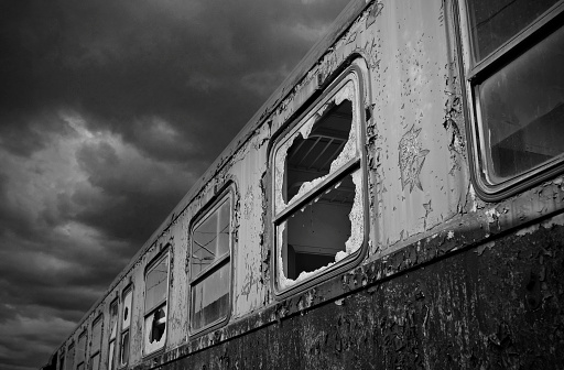 At a lost place. An old passenger car with smashed windows, black storm clouds piling up at a station at the end of the world.