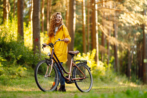 Smiling woman with curly hair in  a bicycle in a sunny park